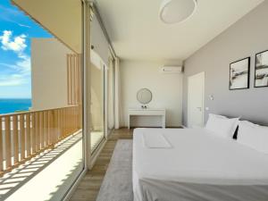 een slaapkamer met een bed en een balkon met uitzicht op de oceaan bij Mèla Twin Villa Green Coast in Himare