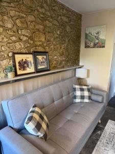 ein Sofa im Wohnzimmer mit einer Steinmauer in der Unterkunft Hart Cottage in Castle Cary