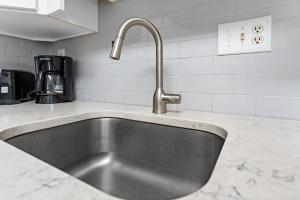 a kitchen sink with a faucet on a counter at North OC Condo 2BR w pool, private hot tub & views of Fenwick Lighthouse in Ocean City +16 photos