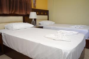 two beds in a hotel room with white sheets at Hotel Artan in Ishull-Shëngjin