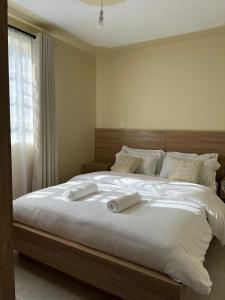 a bedroom with a large bed with two towels on it at Noble Park Apartments in Kiserian