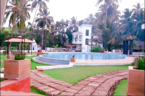 a swimming pool in front of a house with palm trees at Luxury 1BHK Premium Furnished Flat,WiFi, Near BAGA in Arpora