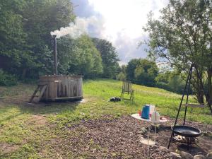 a grill in a field with a table and a chair at Glamping with outdoor wood-fired hot tub in Vissenbjerg +3 photos
