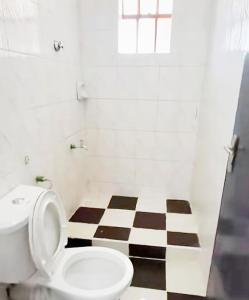 a bathroom with a toilet and a checkered floor at Riva in Nairobi +4 photos