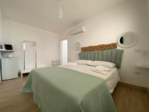 a white bedroom with a large bed with a green blanket at Isid'Oro Rooms - 50m dal mare in Sant'Isidoro
