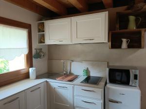 a kitchen with white cabinets and a sink and a microwave at La casetta dei palù in Mosnigo