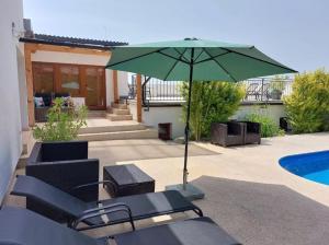 a patio with a green umbrella and chairs and a pool at Village Romantic Apartments by Český Krumlov Adults Only in Střížov