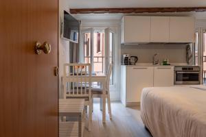 a bedroom with a bed and a table and a kitchen at La Mansardina Padovana - Historic Center in Padova