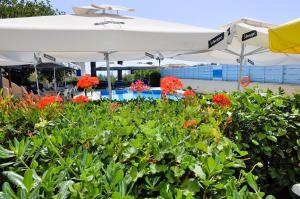a pool with an umbrella and some flowers at Vanas Apartments in Spetses