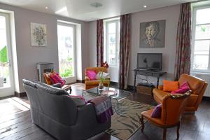 ein Wohnzimmer mit Sofas und Stühlen sowie einem TV in der Unterkunft LES TERRASSES DE CARENNAC in Carennac