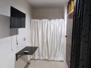 a white curtain in a room with a television at Dalia in Cedro