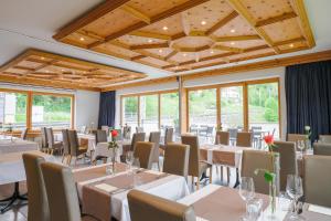 a dining room with tables and chairs and windows at Hotel Grischuna Filisur in Filisur