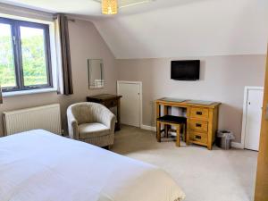 Un dormitorio con una cama, un escritorio y un televisor. en Hay Fields, en Maidstone