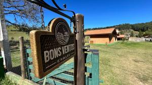 a sign for a brooms farm in a field at Chalés Bons Ventos in São Bento do Sapucaí