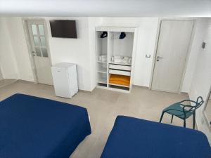 Habitación con 2 camas, TV y silla. en B&B Le Spiagge, en Gaeta
