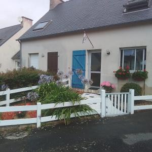 a white fence in front of a house with flowers at Studio charmant in Fouesnant
