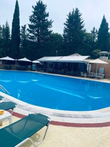 a large blue swimming pool with chairs and umbrellas at Donna's luxury home in Kassiopi 300m from the sea in Kassiopi