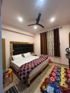 a bedroom with a bed and a ceiling fan at Mayank Palace in Almora