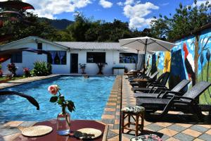 a pool with chairs and a table and an umbrella at Casa de Piedra in Mindo