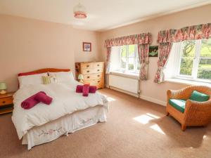 a bedroom with a bed and a chair and windows at Tremorla in Boscastle