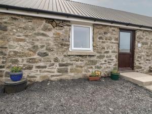 une maison en pierre avec des plantes en pot devant elle dans l'établissement Bathach Mor, à Oban