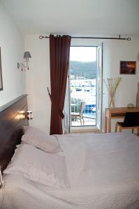 a bedroom with a bed and a large window at Hotel Restaurant L'Europe in Saint-Florent