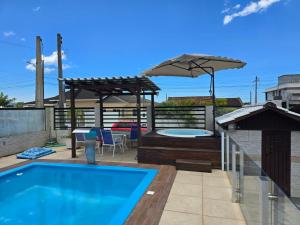 Un patio con piscina y sombrilla. en Casa na Enseada da Pinheira, en Palhoça