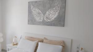 a white bed with white pillows and a picture of wings at Apartamento holidays in Cala en Porter +35 photos