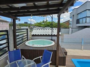 Un jacuzzi en una terraza con sillas y una mesa. en Casa na Enseada da Pinheira, en Palhoça