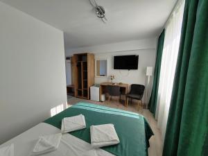 a room with a bed and a table with a television at Casa BEYAZ in Mangalia