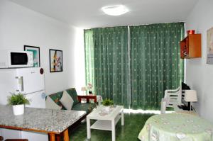 sala de estar con cortina verde y mesa en IG MOMOSOL Apartments, en Puerto Rico de Gran Canaria