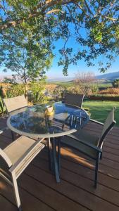 a glass table and two chairs on a wooden deck at la noach in Metulla +14 photos