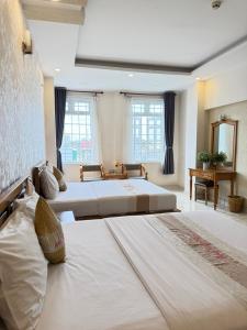 two beds in a large room with windows at Hotel Xuân Ngọc in Ho Chi Minh City +54 photos