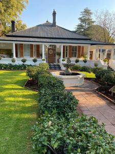 a large white house with a fountain in the yard at Osborne Manor Luxury Guesthouse in Kimberley