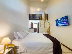 Pousada vila Riveira في بوزيوس: غرفة نوم بسرير ابيض وتلفزيون على الحائط