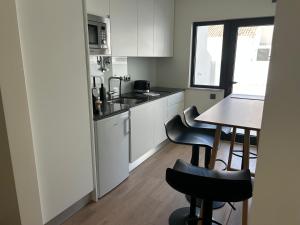 una cucina con mobili bianchi, tavolo e sedie di Casa aOrta Apartments a Faro Altre 13 foto