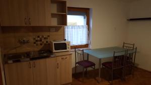 a kitchen with a table and chairs and a microwave at M&M Apartman in Tiszafüred