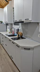 a white kitchen with white cabinets and a sink at The Parkside Villa Apartment II in Berat