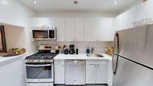 une cuisine avec des armoires blanches et un réfrigérateur en acier inoxydable dans l'établissement Nomad stylish studio in NYC, à New York