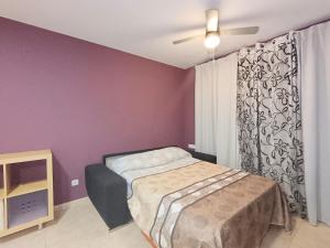 ein Schlafzimmer mit einem Bett in einem Zimmer mit lila Wänden in der Unterkunft Ayf 200m del mar 2 piscinas, pista de padel y gym in Oropesa del Mar + 37 Fotos