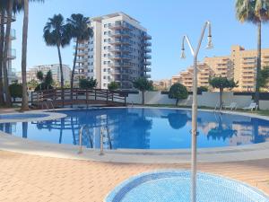 einem großen Pool mit Palmen und einem Gebäude in der Unterkunft Ayf 200m del mar 2 piscinas, pista de padel y gym in Oropesa del Mar