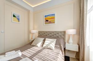 a white bedroom with a bed and two lamps at Bentley Home Sopot in Sopot