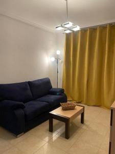 ein Wohnzimmer mit einem blauen Sofa und einem Tisch in der Unterkunft Apartamento con terraza, piscina y vistas en Oropesa del Mar Edificio Torremar in El Borseral