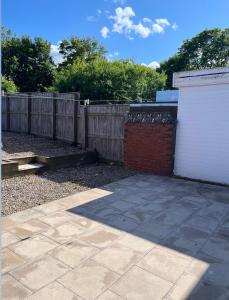 a backyard with a fence and a brick wall at Beautiful holiday home South Beach Blyth 3 minute walk to the beach in Newsham