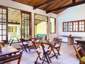 Pousada vila Riveira في بوزيوس: مطعم به طاولات وكراسي ونوافذ خشبية
