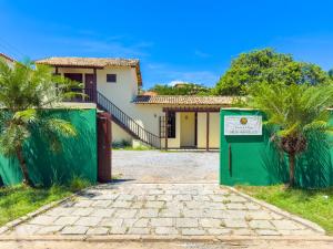 Pousada vila Riveira في بوزيوس: منزل به بوابة خضراء ونخل