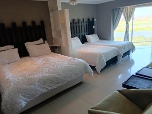 a bedroom with two beds and a couch and a window at Gaia Hydro-Spa and Guest House in Cape Town