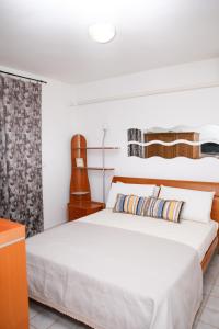 a white bedroom with a bed and a guitar at Appartamento Stefano in Scalea