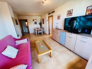 a living room with a pink couch and a large tv at Punta Cormoran by Alina365 in La Manga del Mar Menor