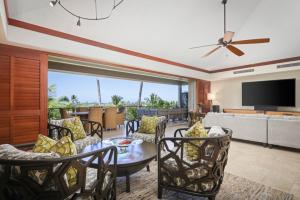 un soggiorno con tavolo, sedie e televisione di 3BD Ke Alaula (210B) Villa at Hualalai Resort a Kukio